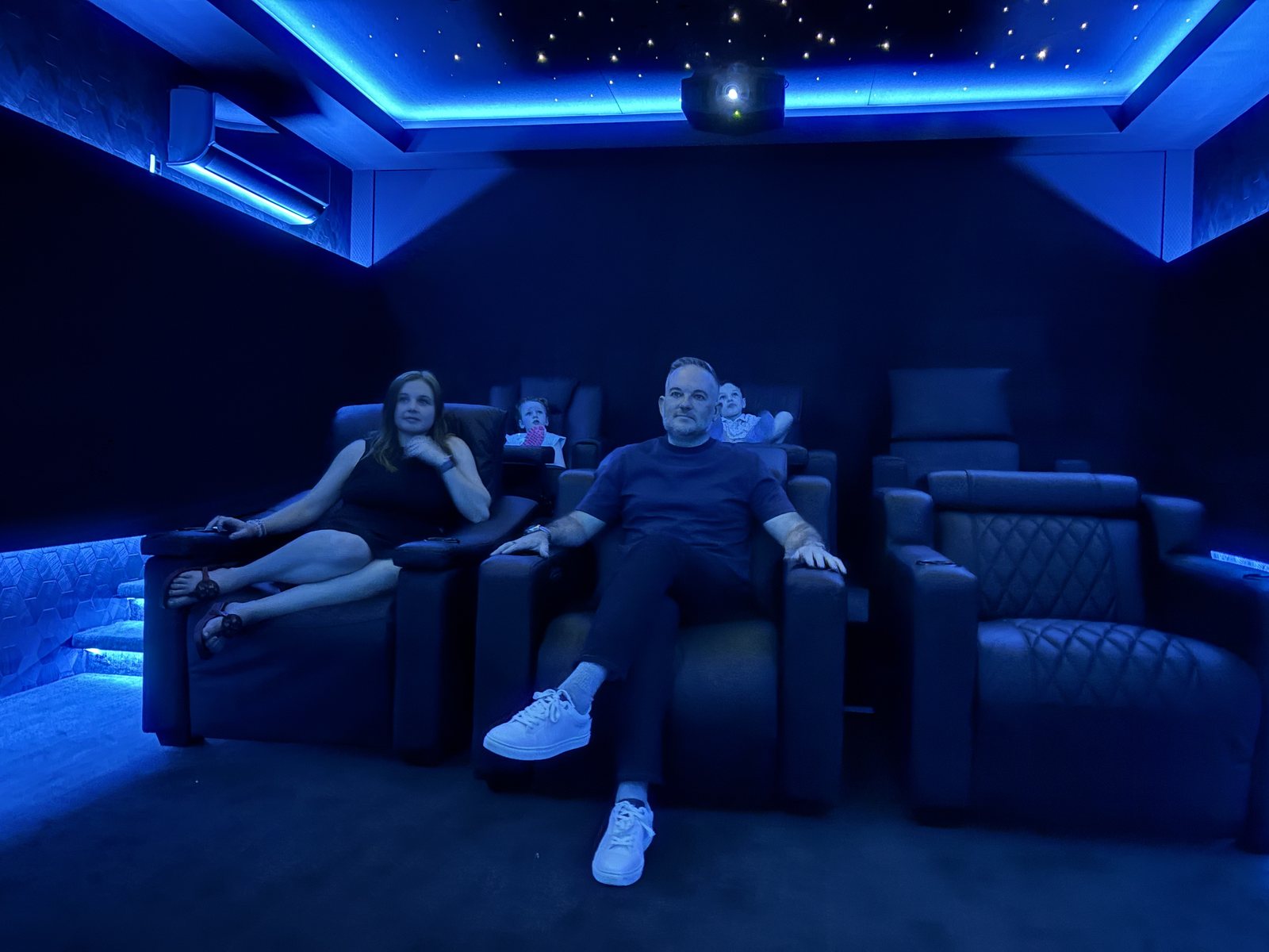 Custom Boston Automations home theater with fiber-optic star ceiling, blue cove lighting, and tiered leather recliners