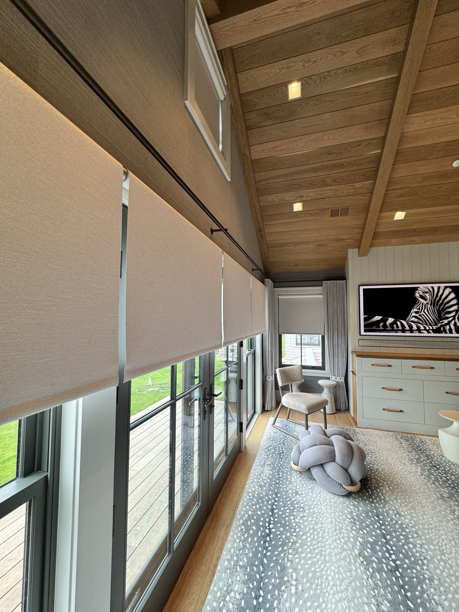 Coastal residence with motorized roller shades under a vaulted wood ceiling