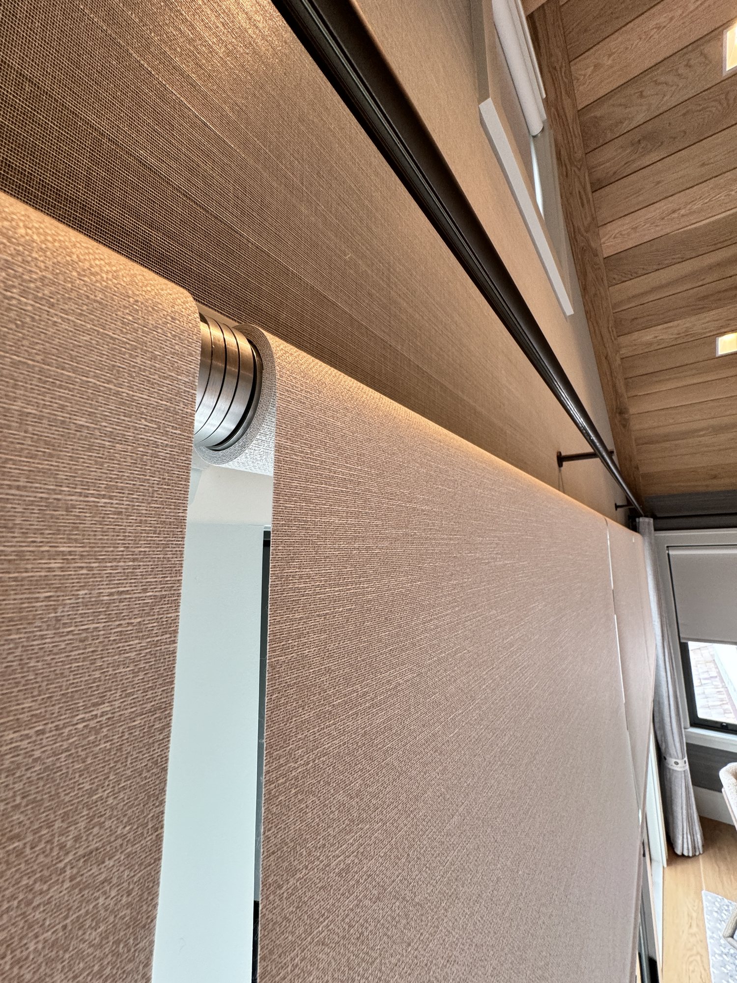 Roller shades installed in a warm wood room